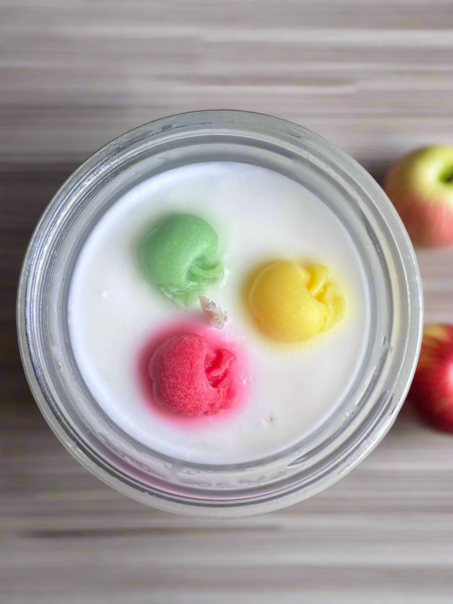 Garden Wick Apple Orchard 100% soy candle with colorful apple wax embeds, featuring the fresh scent of ripe apples with bright fruit notes and a touch of spice. Fragrance notes include orange peel, nutmeg, apple, clove, and vanilla for a cozy orchard-inspired aroma.